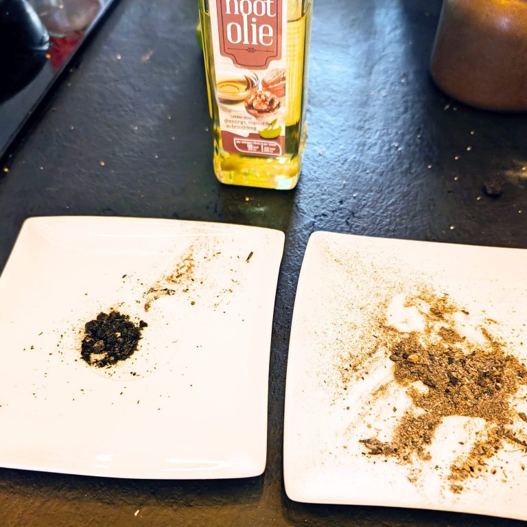 Zwarte en groene kruiden liggen op twee witte borden naast een fles olijfolie.