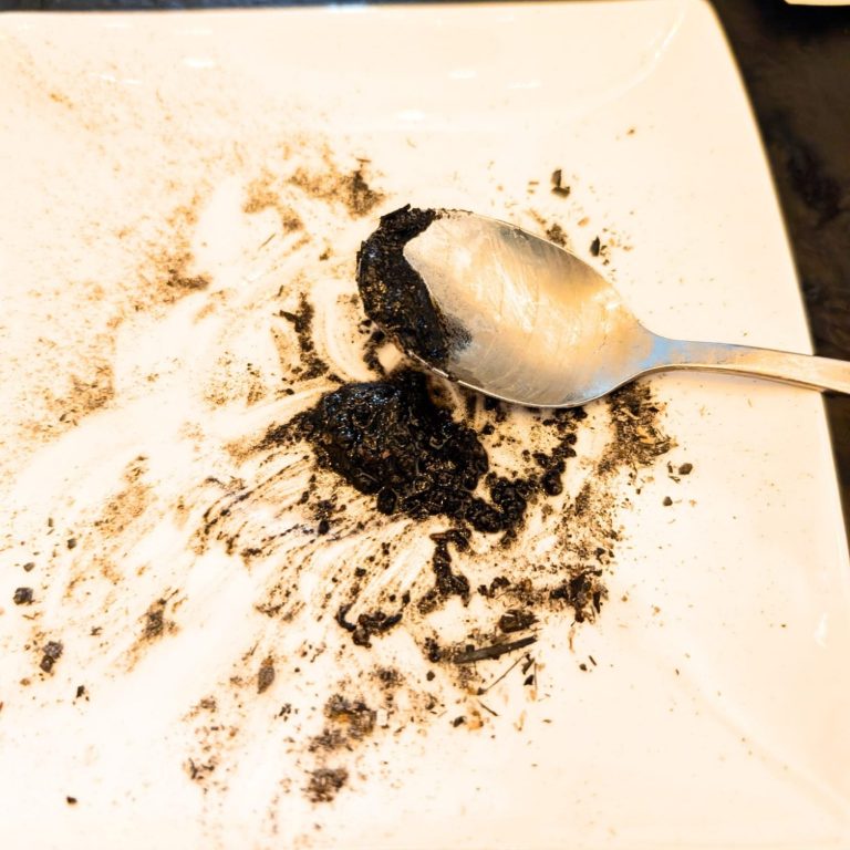 Een lege plaat met een lepel en restjes donkere, plakkerige substantie.