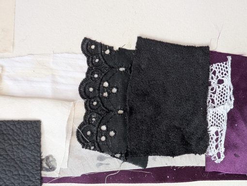 Diverse stoffen in zwart, wit en paars met kant en versieringen.