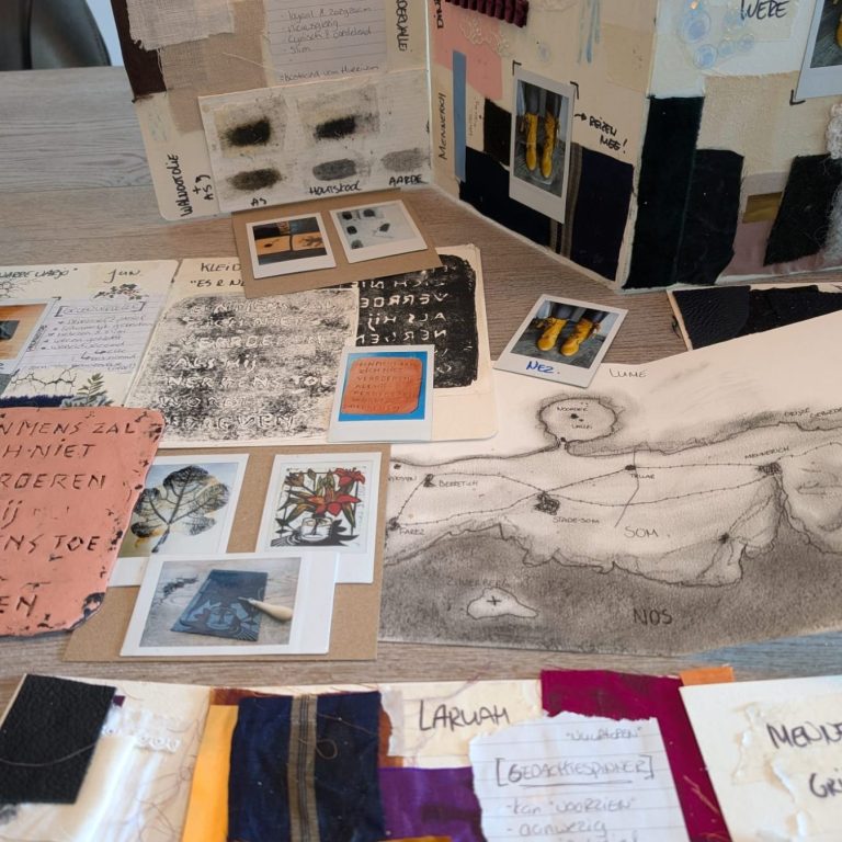 Creatieve collage met verschillende materialen, foto’s en tekeningen op een tafel.