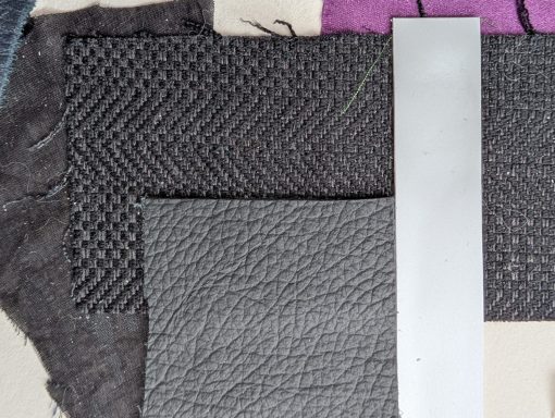 Twee stoffen in verschillende texturen, met een metalen strip tussenin.