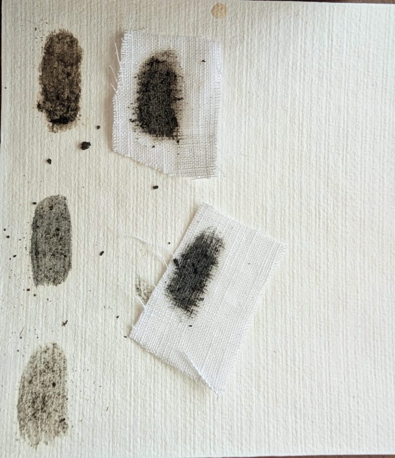 Vijf vlekken van verschillende kleuren op een vel papier, enkele met doekjes.