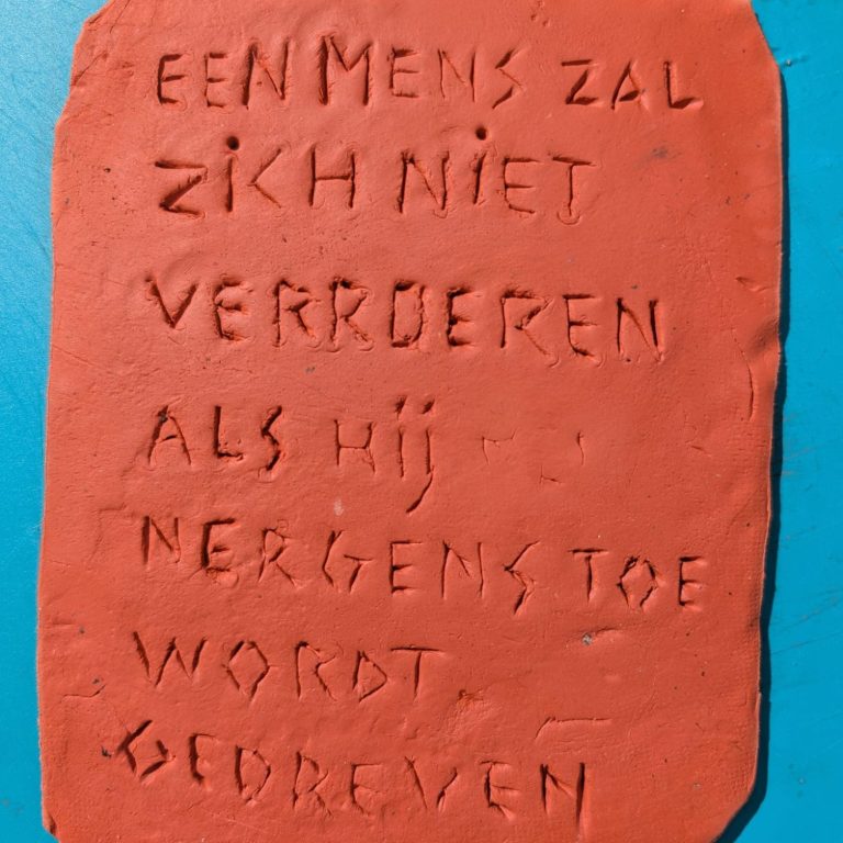 Rood kleibord met gegraveerde tekst over persoonlijke verandering en ontwikkeling.